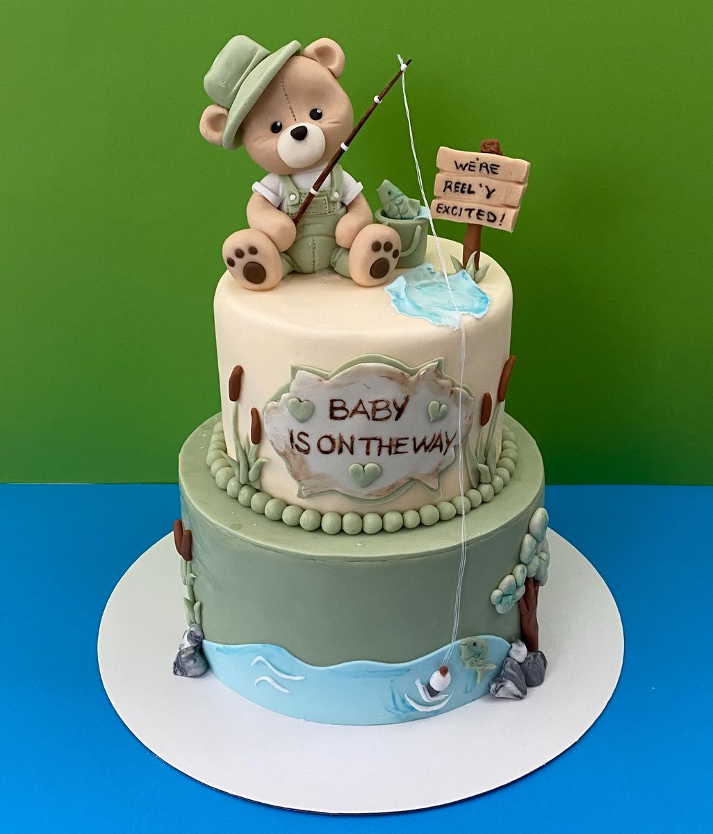 Sage and cream baby shower cake with a fishing teddy bear and a Baby is on the way sign