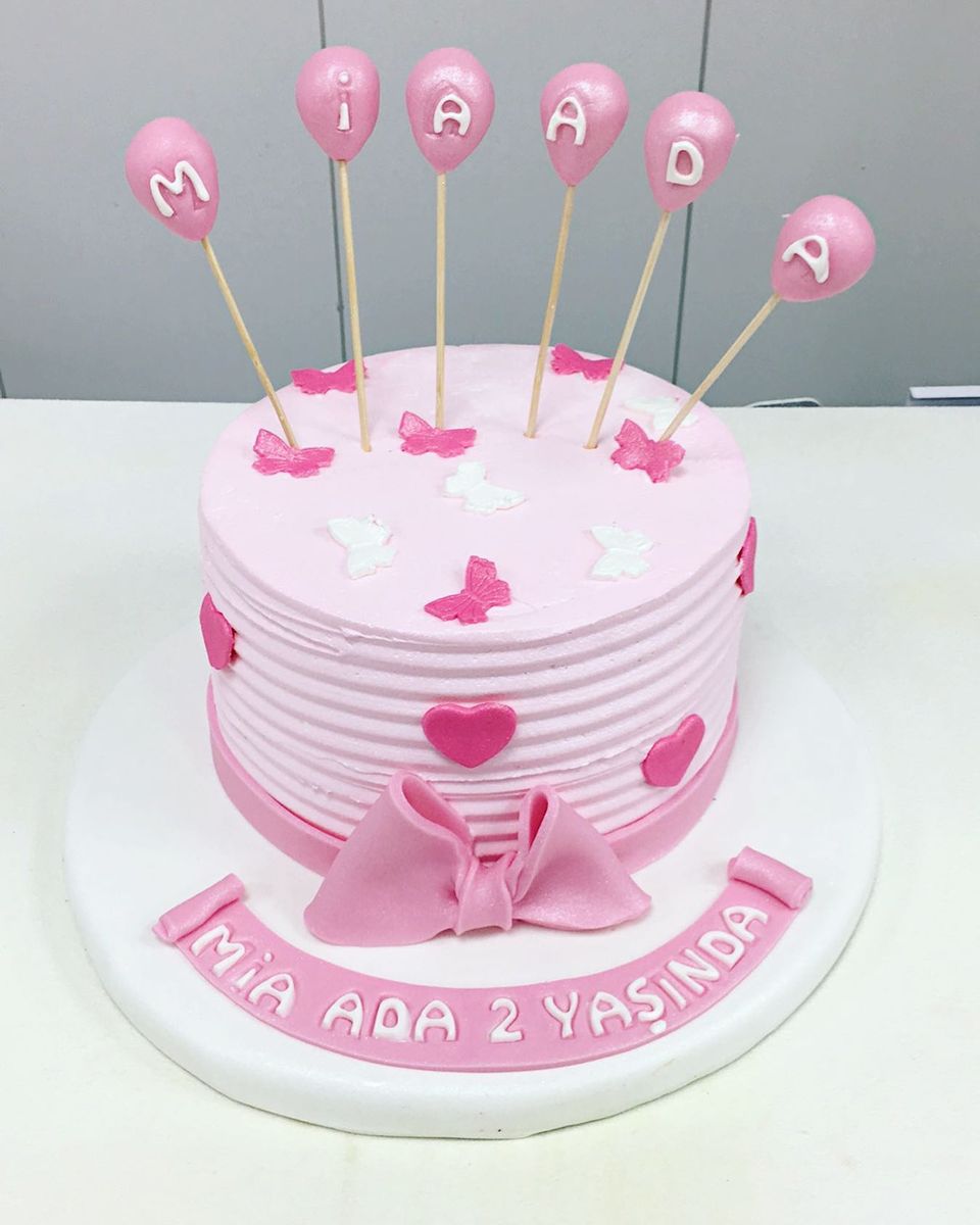 Pink celebration cake with fondant butterflies and a cluster of balloon cake pops